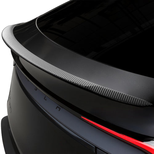 Close-up of a carbon fiber rear spoiler fitted above the light bar on a dark Model Y Juniper