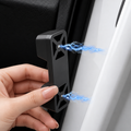 A hand holds a black plastic car door jammer against a white car door, with blue lightning graphics illustrating the electric shock effect.