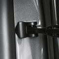 Close-up of a black cover surrounding the check-arm mounting point on a gray door jamb.