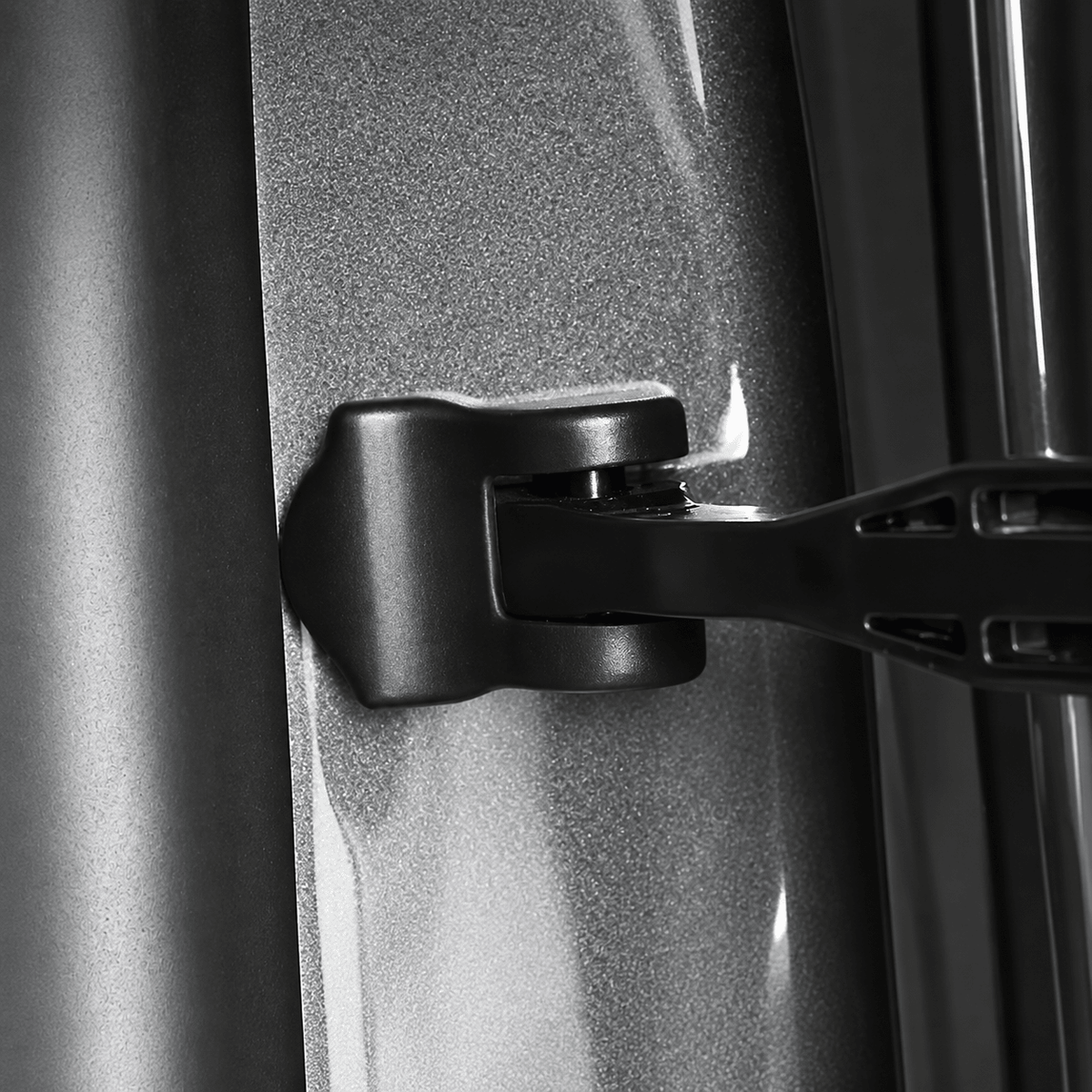 Close-up of a black cover surrounding the check-arm mounting point on a gray door jamb.