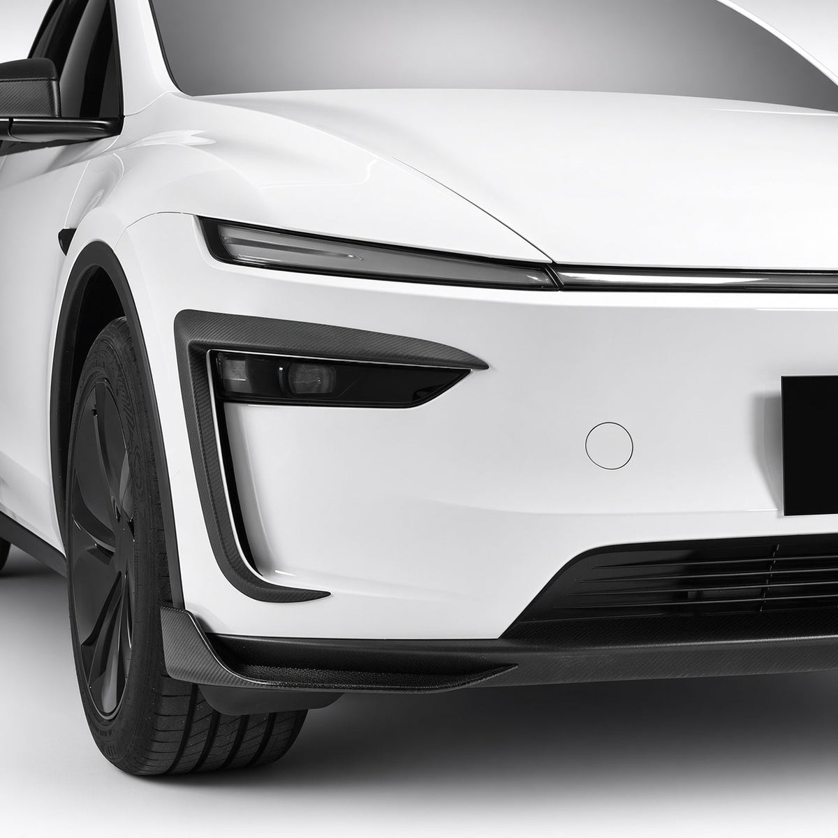 Angled front view of a white Model Y with carbon-fiber trim at the bumper corners
