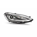Front angled view of a projector headlight with black housing and silver inner trim.