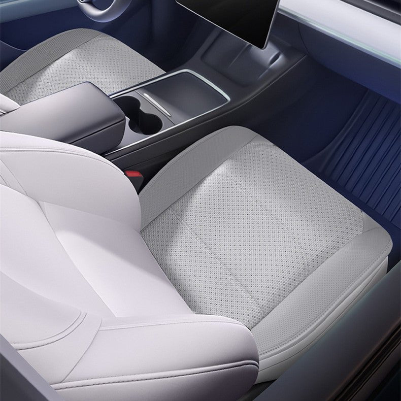 Top-down view of a white perforated cushion pad fitted over the seat base beside the center console.