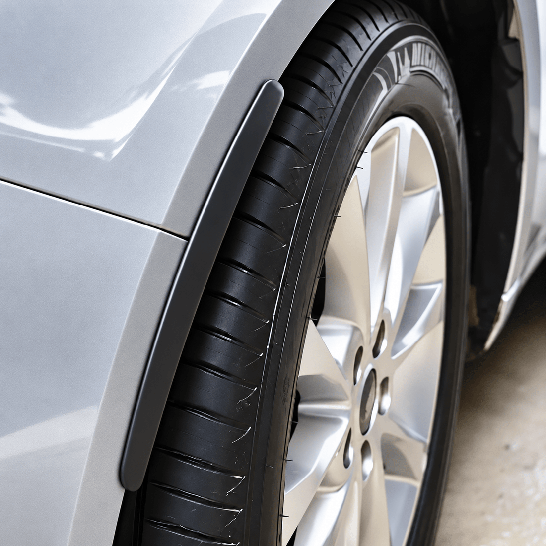 Pair of black wheel arch protector strips shown beside a strip fitted above a car tire